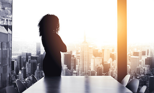 Women looks out of boardroom window while considering the difference between governance and compliance